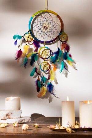 Attrape-rêves indiens artisanal multicolore suspendu avec plumes vibrantes et toile tissée, décoré près de chandelles blanches